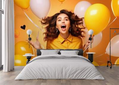 Portrait of wow excited amazed woman with open mouth and colored helium balloons on a yellow background for congratulations on the holiday day Wall mural