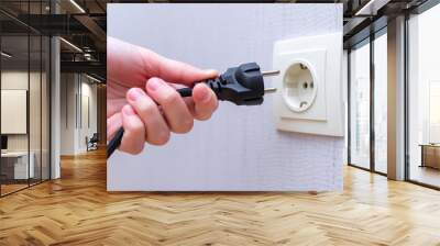 Ready to connect. Plugging electrical, black plug in electric socket on wall. Wall mural