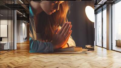 Religion woman folded her hands in prayer. Praying with the bible at evening at home and turn to god, ask for forgiveness and believe in goodness. Christian life and faith in god Wall mural