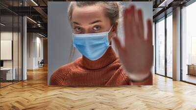 Stop the virus and epidemic diseases. Healthy woman in blue medical protective mask showing gesture stop. Health protection and prevention during flu and infectious outbreak Wall mural