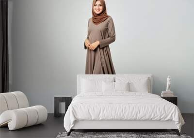 Studio shot of a beautiful satisfied cheerful smiling young muslim woman wearing hijab and traditional dress posing on a white background Wall mural