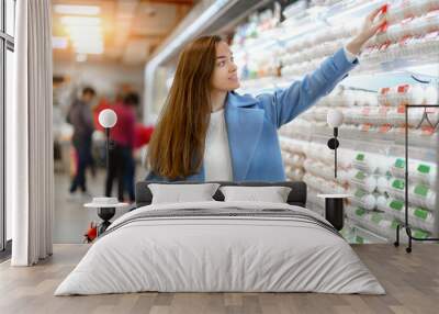 Woman buyer with cart in the grocery shop during choosing and buying fresh chicken eggs while shopping food Wall mural