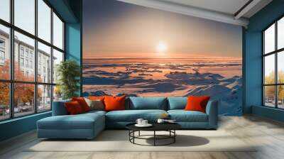 Bright sunset panorama view in Antarctica. Orange sun lights over the snow covered polar surface. Picturesque winter landscape. The beauty of the wild untouched Antarctic nature. Wall mural