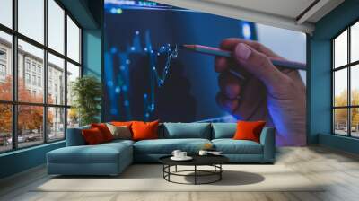 Business man hand holding pencil points to stock market graph analysis on monitor screen. Economic and financial concept. Seletive focus. Wall mural