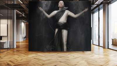 dancer in beige spandex jumpsuit posing with flying flour on black background in Studio Wall mural