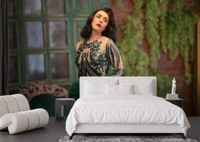 elegant caucasian girl in a luxurious long sequins lace dress with a green fluffy boa in her hands posing in the retro room with vintage luxury furniture Wall mural