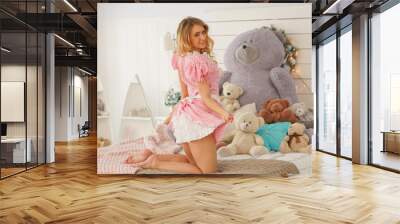 Pretty adult girl in pink cute dress in her white bedroom with many plush teddy bears alone Wall mural