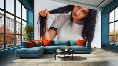 Funny portrait of a cute woman. Halloween portrait. Woman holding her hairs with two hands. Female making funny facial expressions. Portrait of a happy playful girl with dark hair Wall mural