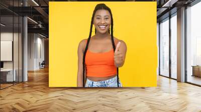 Approval gesture. Agree sign. Excellent idea. Joyful smiling African woman showing thumb up success symbol isolated on orange background. Wall mural