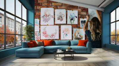 art studio workspace. painter artwork. woman sticking watercolor drawings of flowers and animals to the wall Wall mural