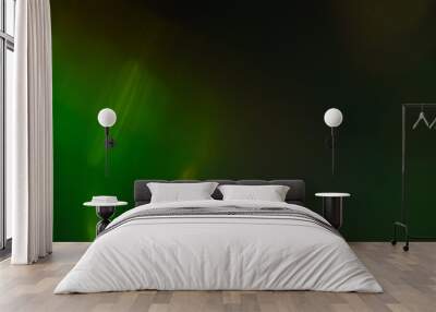 Blurred green abstract lens flare on dark background. Defocused glow effect. Wall mural