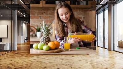 child health and development. useful and tasty drink. vitamin orange juice for balanced nutrition. little girl pouring fresh fruit beverage from a bottle Wall mural