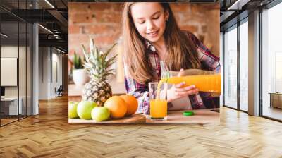 Child health and development. Vitamin orange juice for balanced nutrition. Little girl pouring fresh fruit drink from bottle. Wall mural