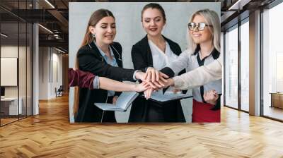 Corporate marketing team. Unity and cooperation. Smiling business women putting hands together. Wall mural