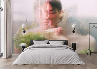 Creative portrait. Spa therapy. Sensual woman face blur silhouette with green leaves behind steamed glass with rain drops double exposure effect. Skin care. Beauty wellness. Wall mural