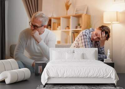 Family problem. Parent generation. Difficult relationship. Depressed offended father and son feeling embarrassed after conflict sitting sofa home interior. Wall mural