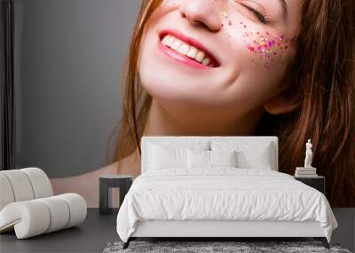 Happy young woman. Party fun and freedom. Redhead female with toothy smile and sparkles on cheeks. Copy space. Wall mural