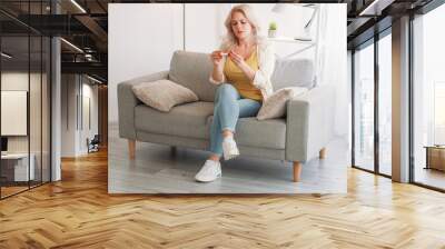 Maternity expectation. Worried woman. Unexpected news. Serious lady getting negative test result sitting sofa light room interior. Wall mural