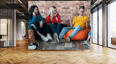 Modern work culture. Group of millennials relaxing on bean bags. Communication and discussion. Business team diversity. Wall mural