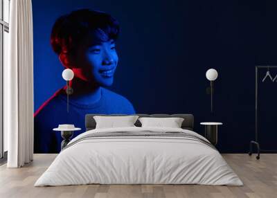 Neon light man. Cyberpunk banner. Happy smile. Positive emotion. Portrait of cheerful Asian guy in bright colorful shining red blue glow isolated on dark empty space background. Wall mural