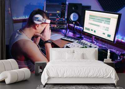 Tired DJ after hard work in sound recording studio. Exhausted DJ after overtime, he has problems and headache. Tired sound producer hiding his eyes.  Wall mural