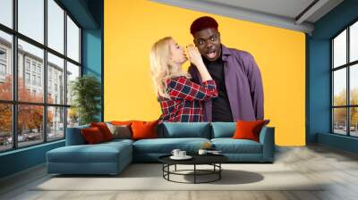 Woman gossip. Secret share. Multiracial friendship. People diversity.  friends sneaky lady whispering rumor hearsay to  shocked man isolated on yellow background. Wall mural