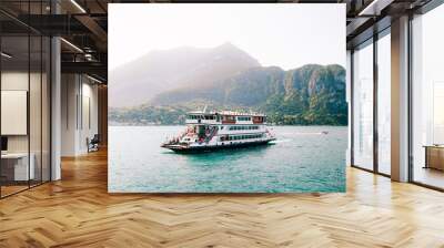 Peaceful Lake Como (Italian Lago di Como). Big ferry boat transportation with cars and people in amazing harbor. Small coastal resort town in Alps. Scenic panorama. Nautical vessel. Forest and hills. Wall mural