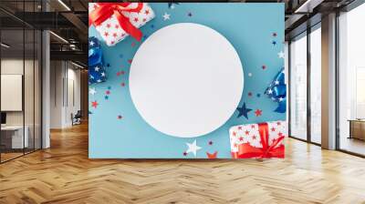 American Independence Day gift themes. Top view flat lay of gift boxes in national colors, patriotic sparkles on light blue background with blank circle for greeting or promotion text Wall mural