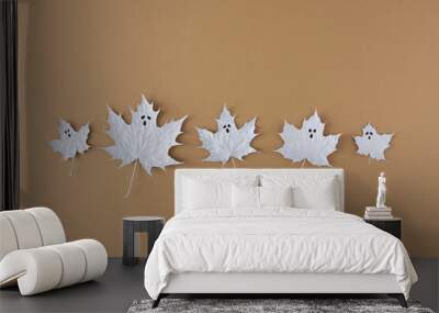 Creative flat lay with autumn leaves painted in white like ghost on beige background. Halloween minimal concept. Wall mural