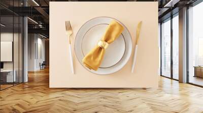 Table setting concept. Top view photo of circle plates with cutlery knife fork and fabric napkin with gold ring on isolated pastel beige background Wall mural