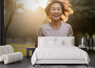 Middle-aged Asian woman running during a sunset in the park Wall mural