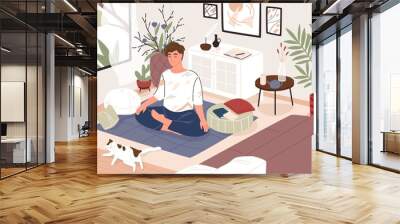 Cute guy or boy sitting cross-legged in his room or apartment and practicing yoga. Young male yogi with crossed legs and closed eyes meditating at home. Flat cartoon colorful vector illustration. Wall mural