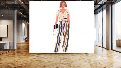 Smiling trendy person demonstrate modern vogue vector flat illustration. Stylish young woman standing in colorful apparel isolated on white. Happy female in summer outfit holding classy handbag Wall mural