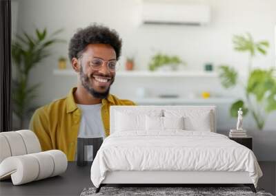 Smiling man in yellow shirt using a smartphone indoors Wall mural