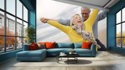  Lively senior couple playing around on beach together Wall mural