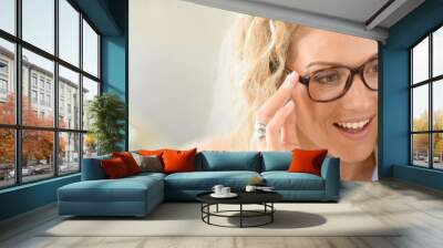 Blond woman at the optical shop, trying eyeglasses on Wall mural