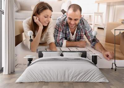 Cheerful couple looking at construction house plan Wall mural