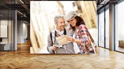 Cheerful couple looking at map, week-end tour Wall mural