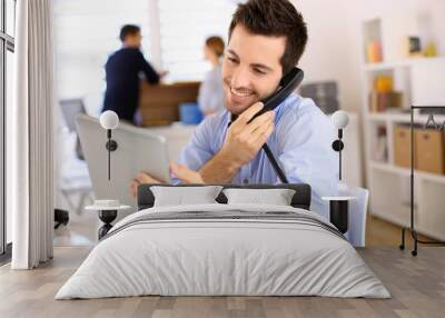 Cheerful man in office answering the phone Wall mural