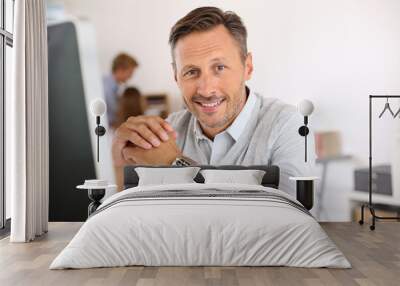 Cheerful man sitting in office and working on desktop Wall mural