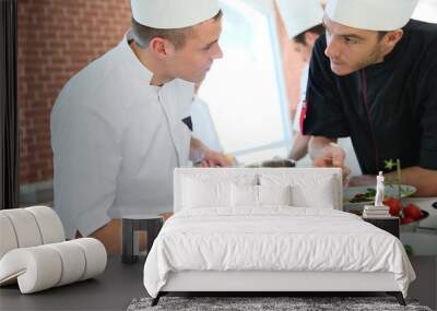 chef with young cook in kitchen preparing dish Wall mural