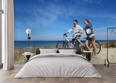 Couple standing on a sand dune with bicycles Wall mural