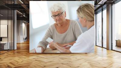 doctor giving pills to elderly woman Wall mural