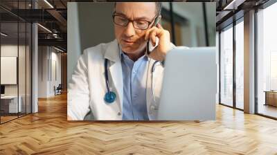 Doctor in office working on laptop talking on phone Wall mural