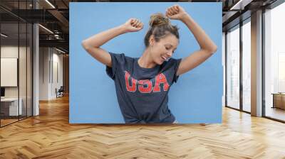 Dynamic girl wearing USA T-shirt dancing on blue background Wall mural