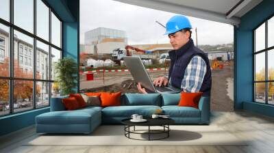 Engineer on construction site with laptop computer Wall mural