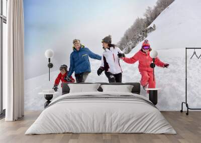 Family of 4 running down in snowy slope Wall mural