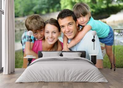 Family relaxing by river in countryside Wall mural