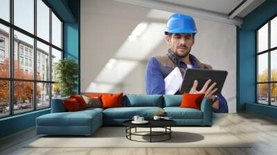 Handsome building expert in hardhat outdoors with tablet and blueprint Wall mural