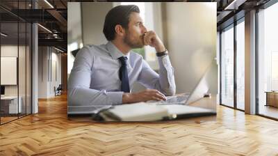 Handsome businessman in modern office looking out Wall mural